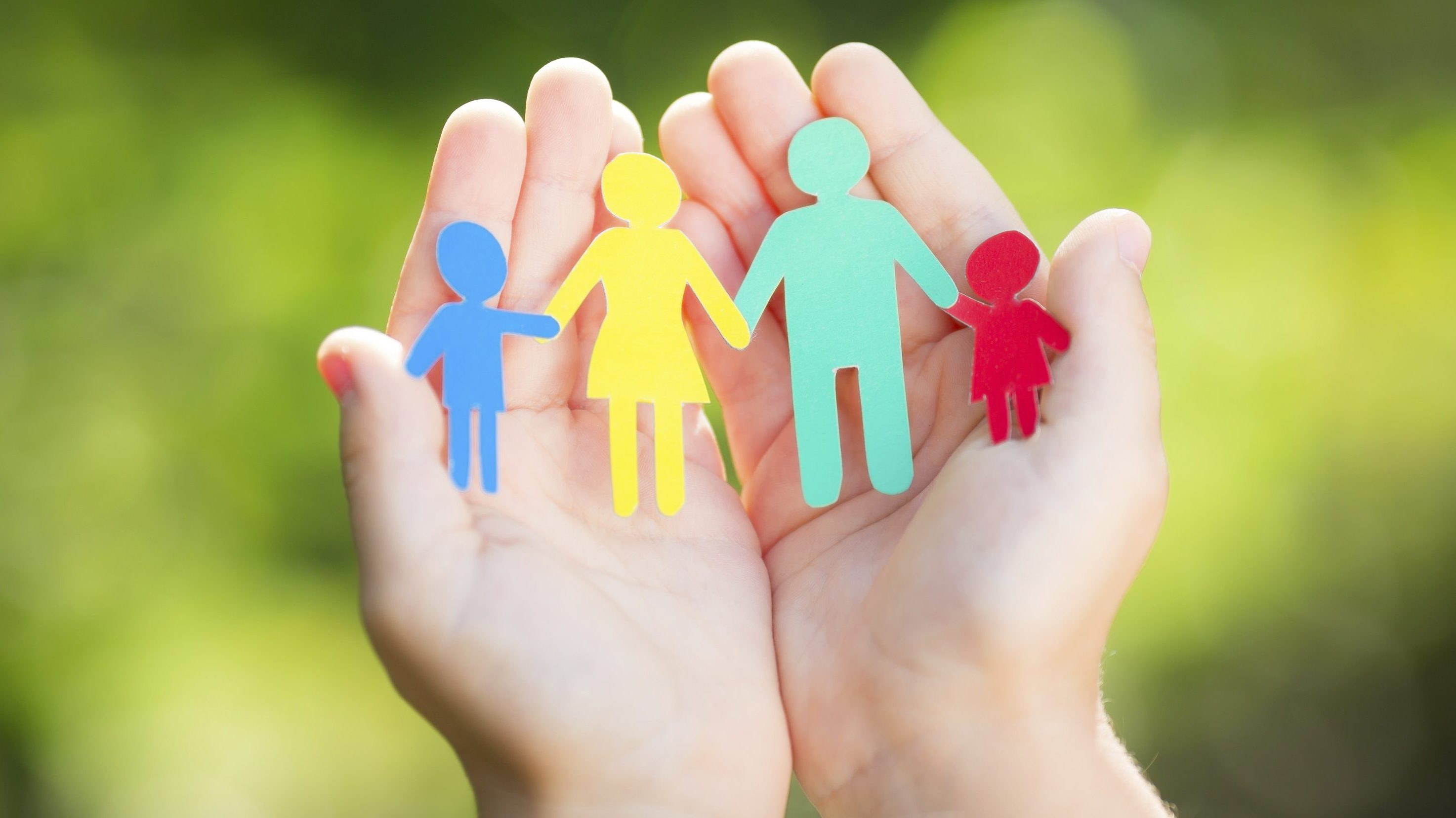Child holding paper family in hands against spring green background